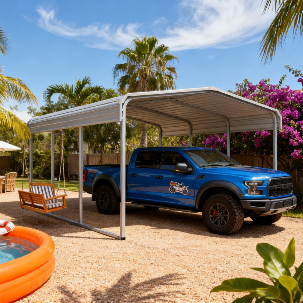 Blue truck parked under a metal carport with palm trees and flowers in the background