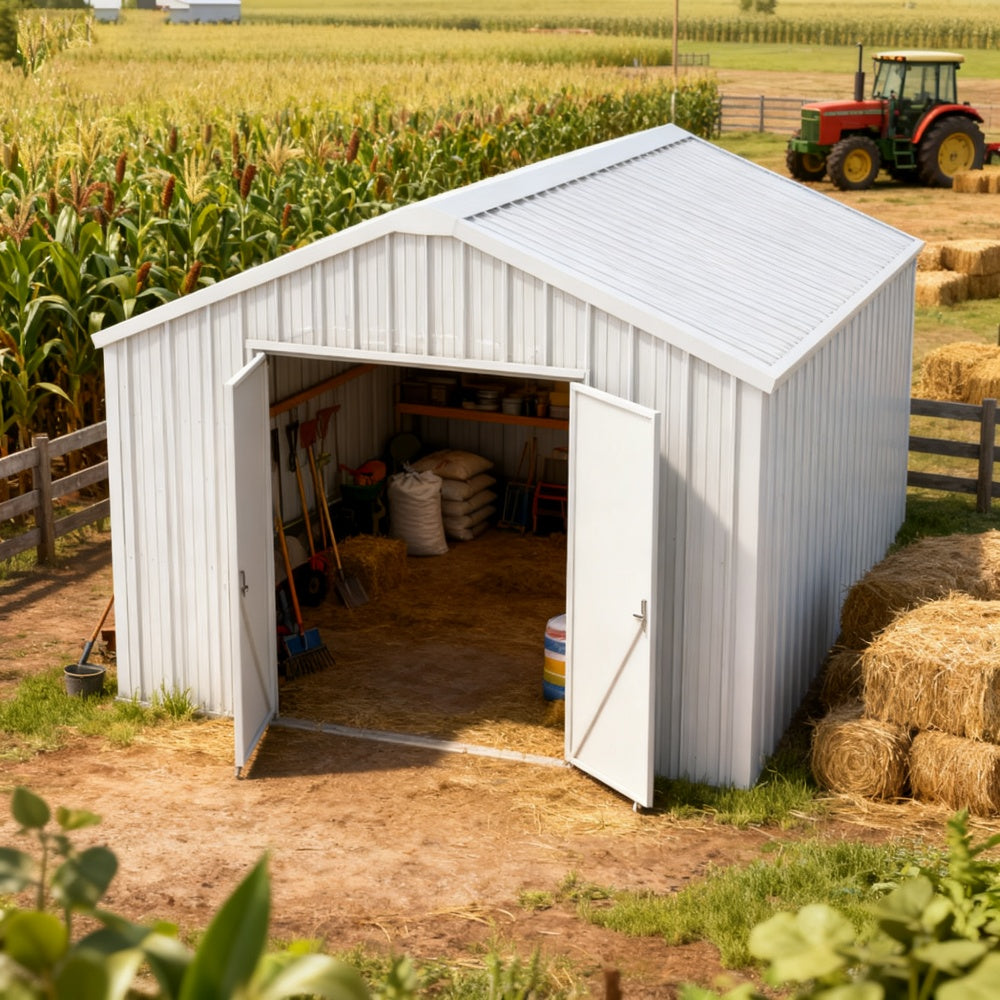 White storage shed with open doors in a rural setting with cornfield and tractor.