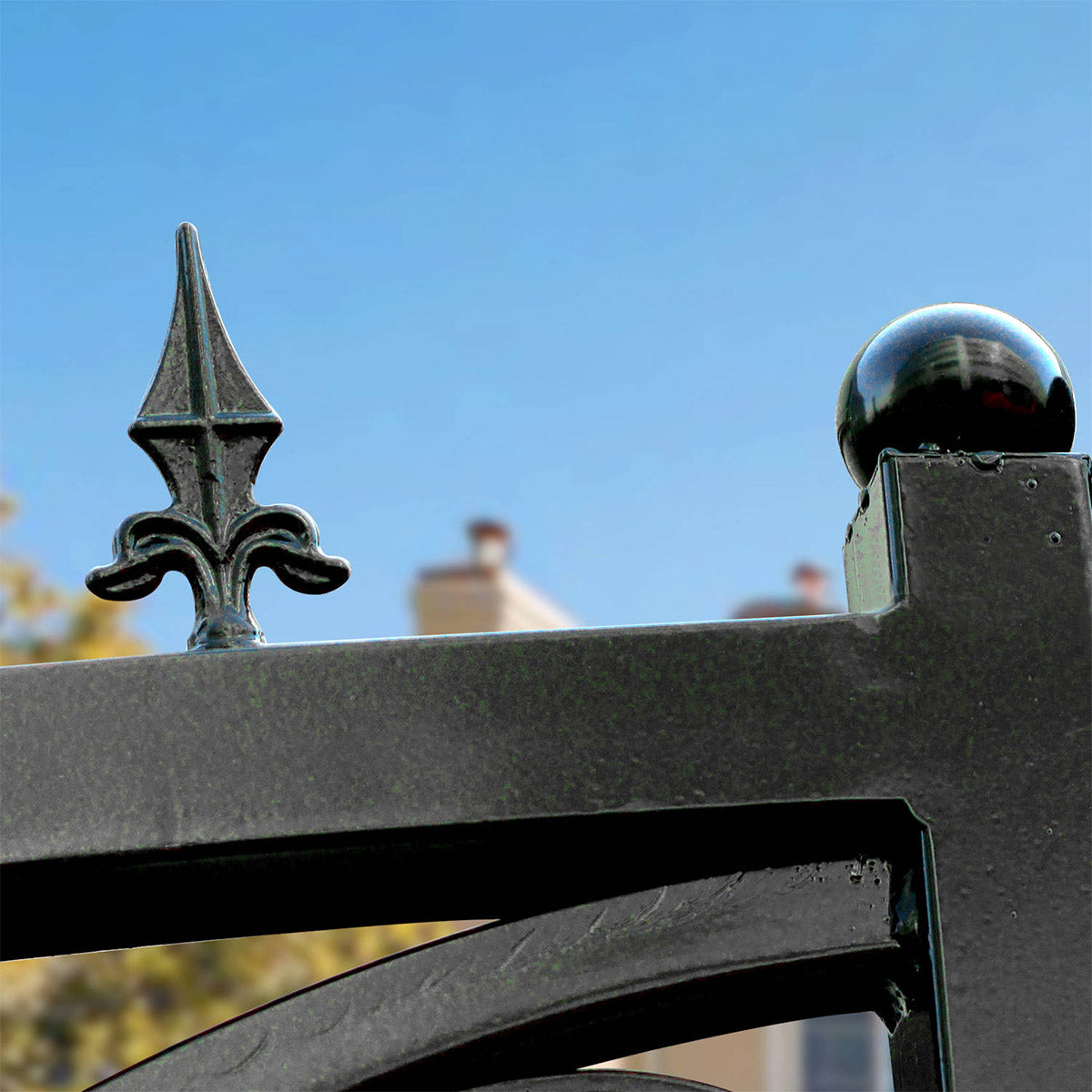 Close-up of a black metal fence or gate with a decorative spear-shaped finial and a glossy spherical ball ornament