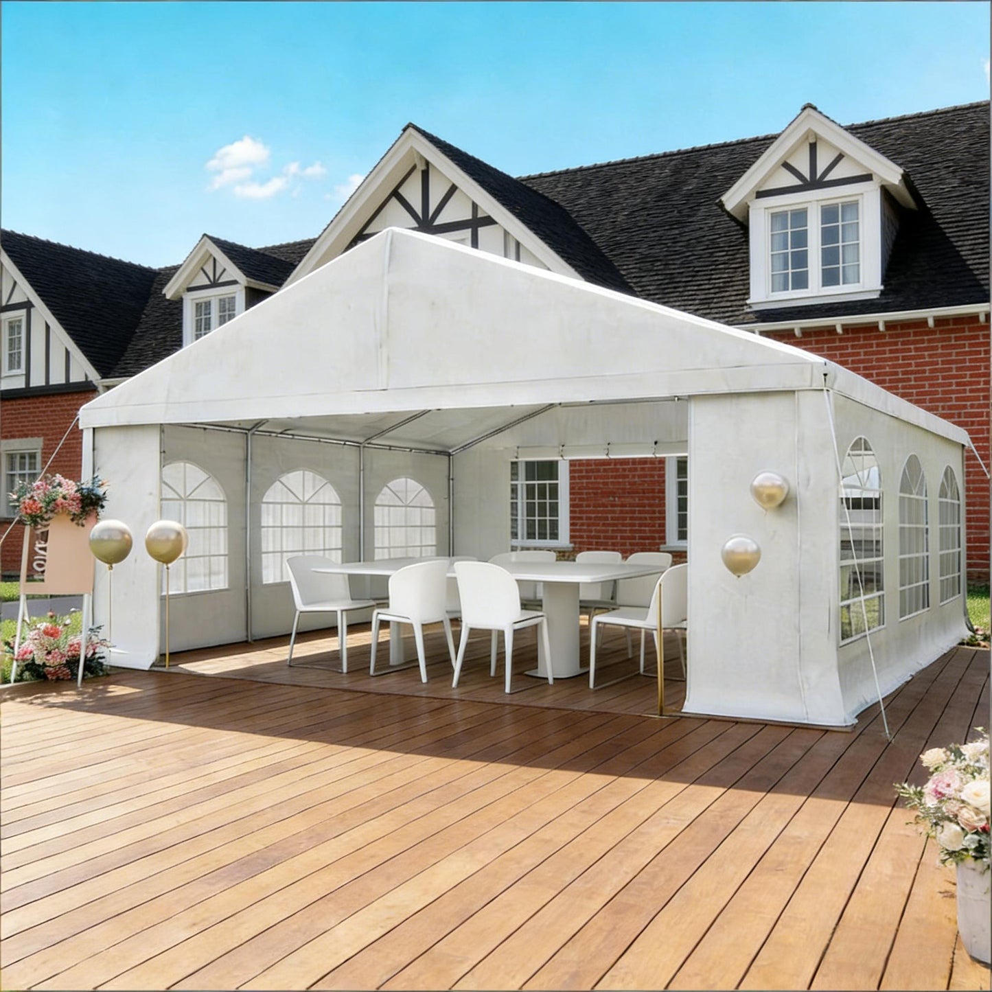 White outdoor canopy tent set up on a wooden deck with chairs and tables underneath, in front of a house.