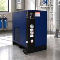 Blue industrial air compressor in a factory setting with pipes and tanks.