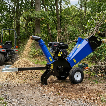 Blue wood chipper in a forest setting with trees and branches around.