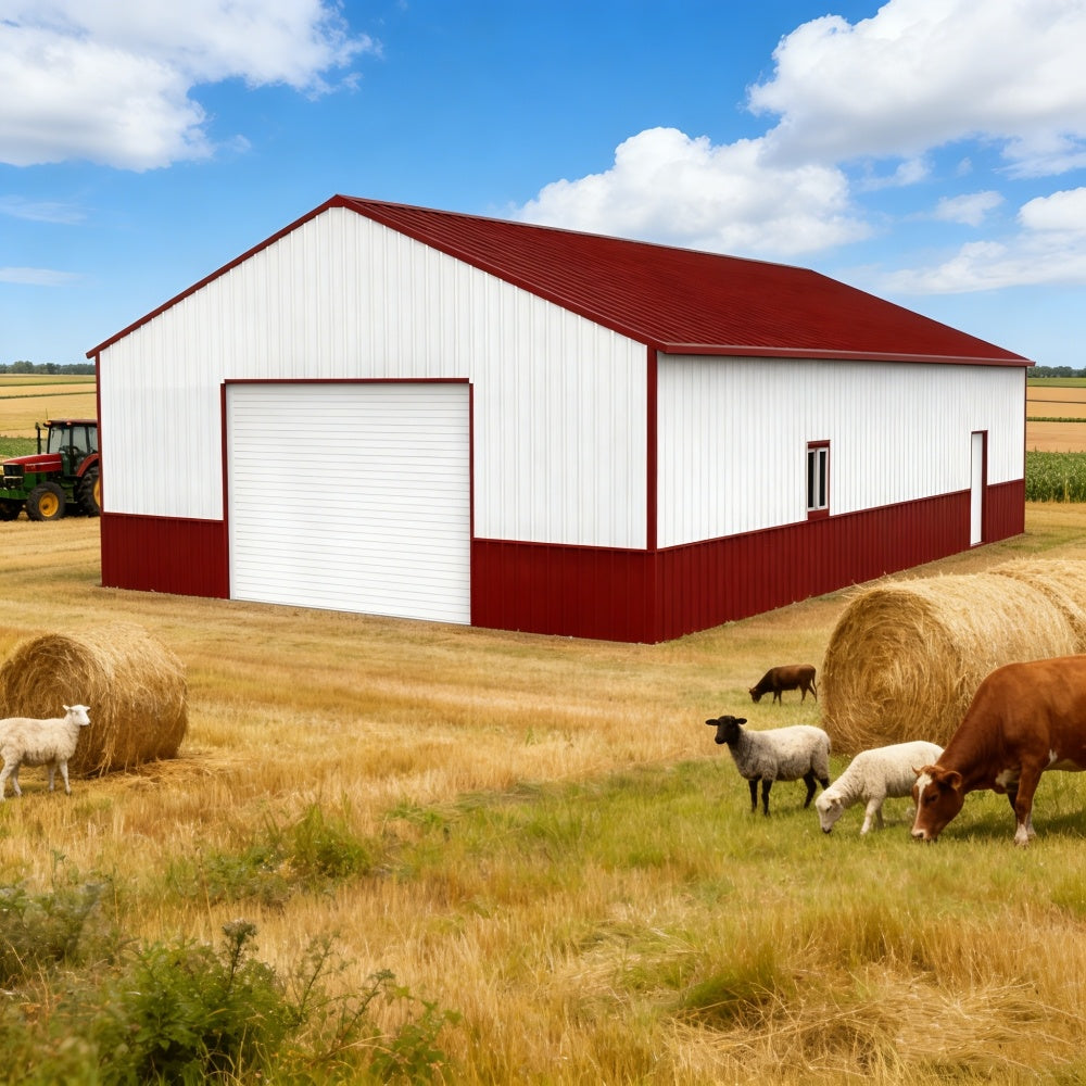 White barn with red roof in a rural setting with hay bales and animals.