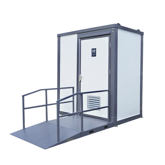 A portable restroom cabin with a gray metal frame, white door and walls, and a ramp with handrails