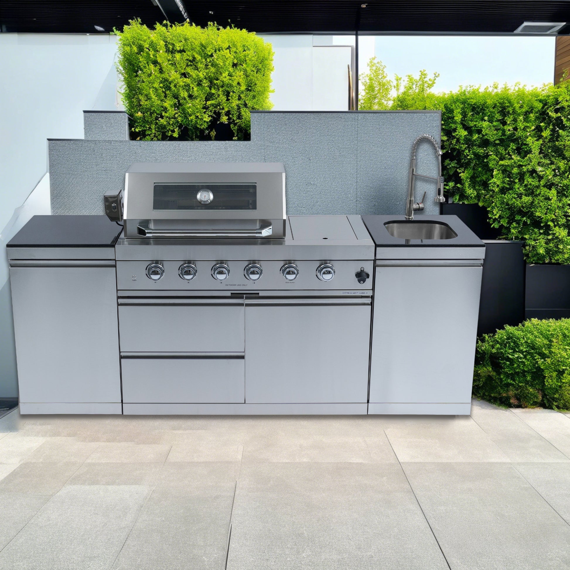Outdoor kitchen with stainless steel grill and sink in a garden setting