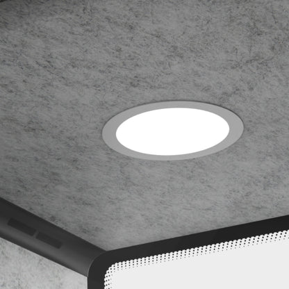 Round recessed ceiling light fixture on a gray concrete ceiling