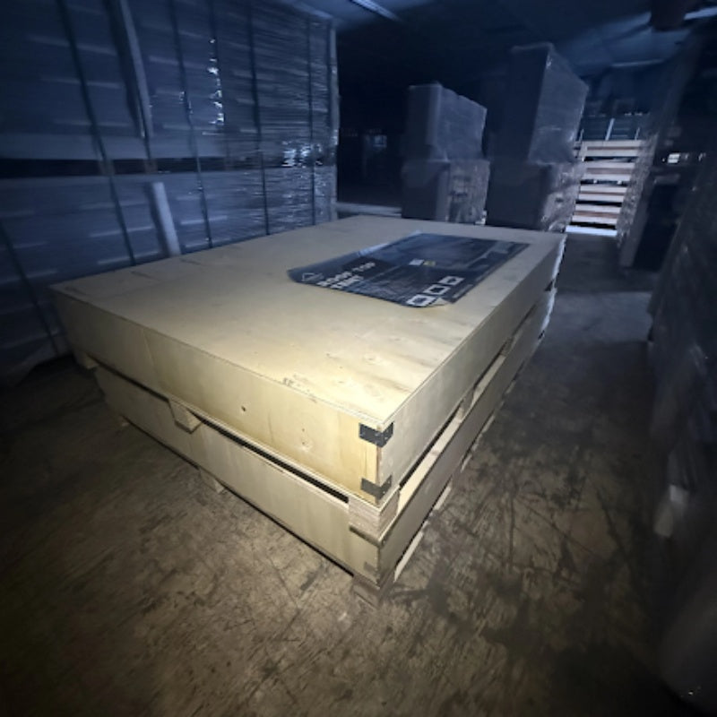 Wooden pallet with a blue label in a dimly lit warehouse.