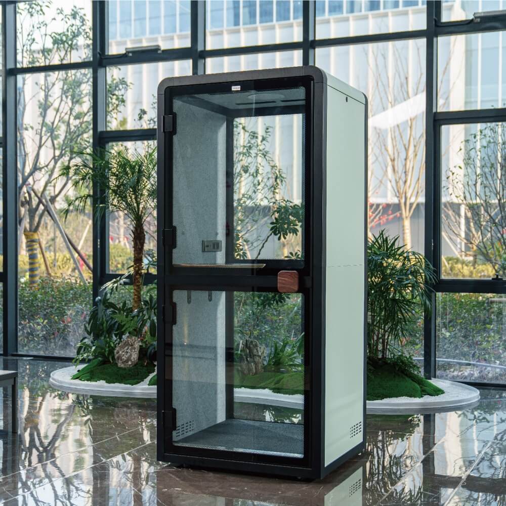 Modern glass enclosure in an indoor setting with large windows and plants.