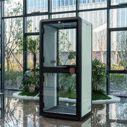 Modern glass enclosure in an indoor setting with large windows and plants.